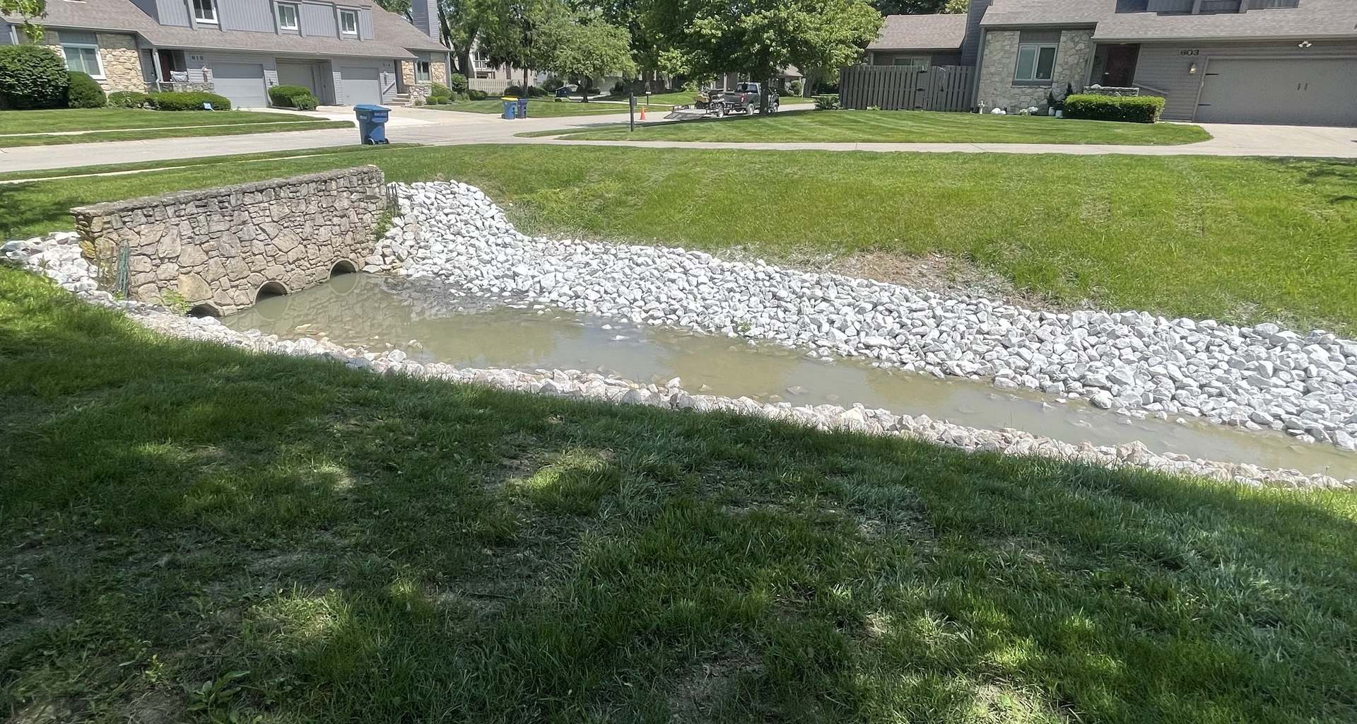 A stone headwall with twin culvert pipes discharging into a rock lined channel