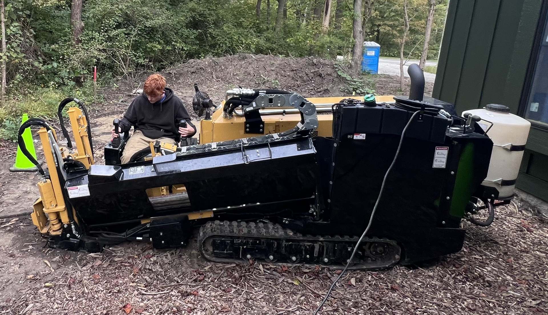 A tracked directional boring rig set up on a residential job, operator at the controls